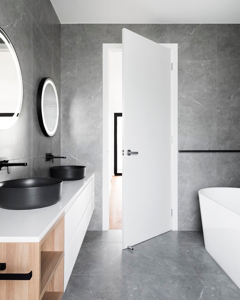 Modern stone-walled bathroom showcasing quartz vanity and double vessel sinks