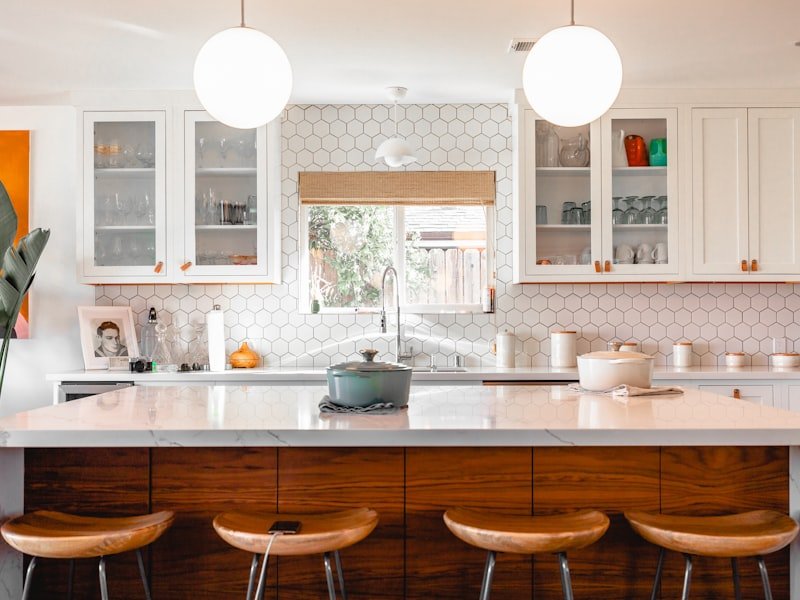 White quartz kitchen island with hexagonal tile backsplash and bar stools
