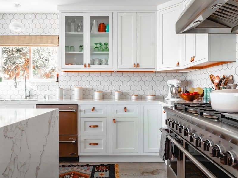 Bright white quartz kitchen with marble-look counter and orange accents