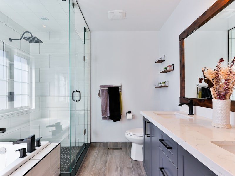 Bathroom with white quartz vanity, glass shower and dark cabinets