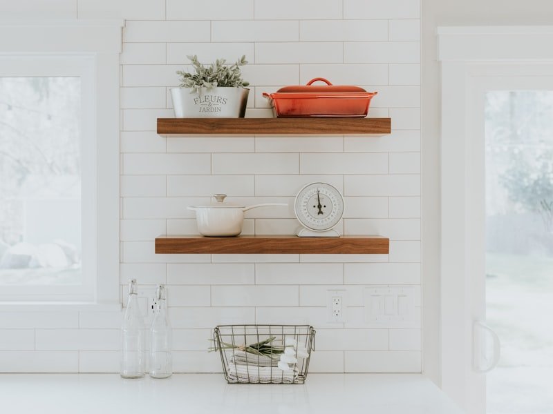White subway-tile kitchen wall with floating wood shelves and white quartz counter